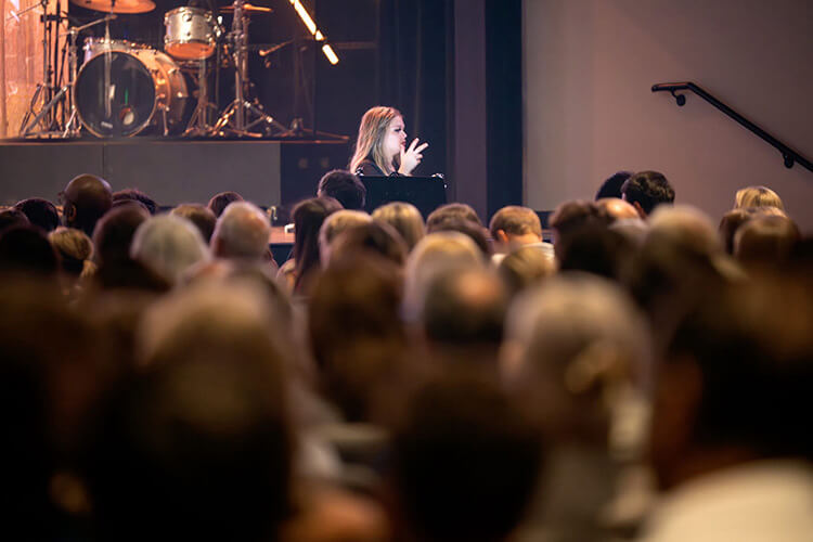 An interpreter in front of a large crowd at a conference